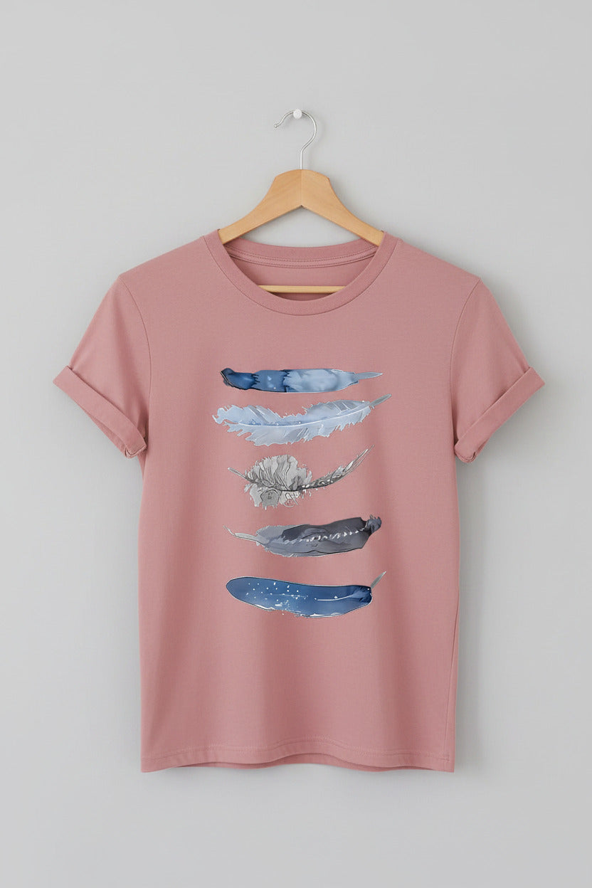 Pink t-shirt with abstract blue designs on a hanger against a denim background