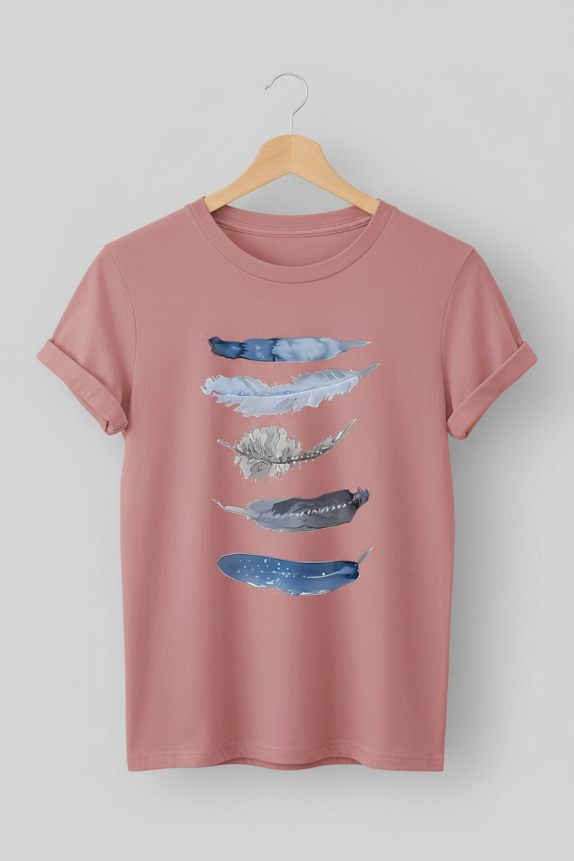 Pink t-shirt with abstract blue designs on a hanger against a denim background
