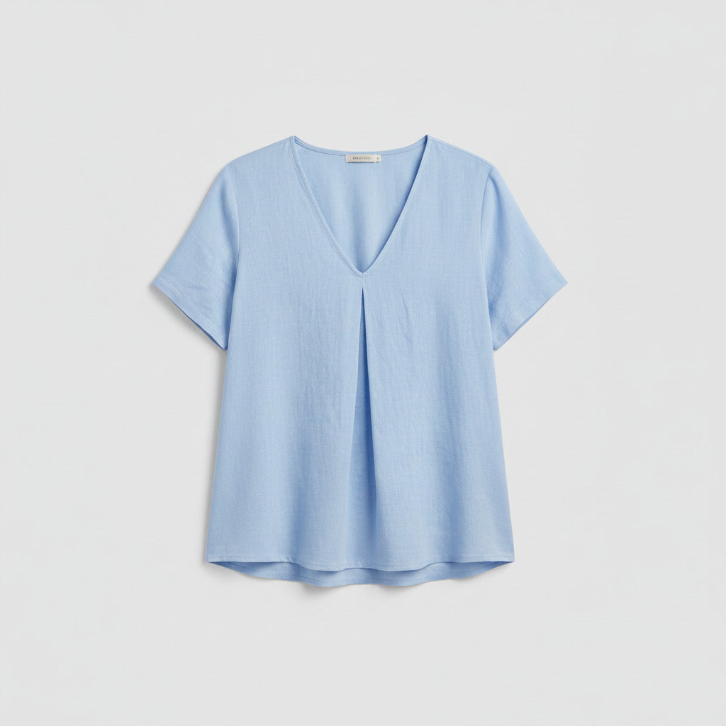 Person wearing a light blue shirt and ripped jeans indoors.